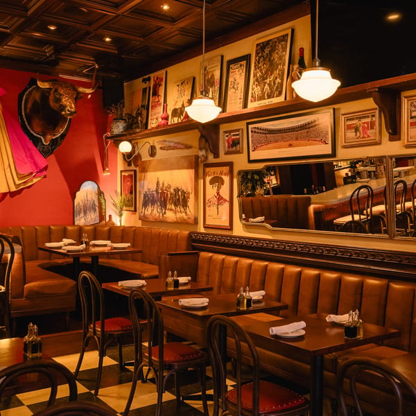 Romesco Mexiterranean Bistro's dining room with bullfighting decor, leather booths, and checkered floors.
