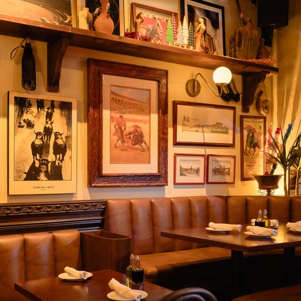 Cozy Romesco Mexiterranean Bistro interior with leather booths, dark wood tables, and bullfighting art on the walls.