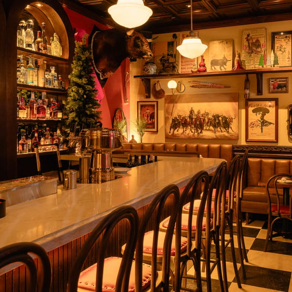 Romesco Mexiterranean Bistro's bar with bullfighting art, a bull's head, and a fully stocked liquor shelf.