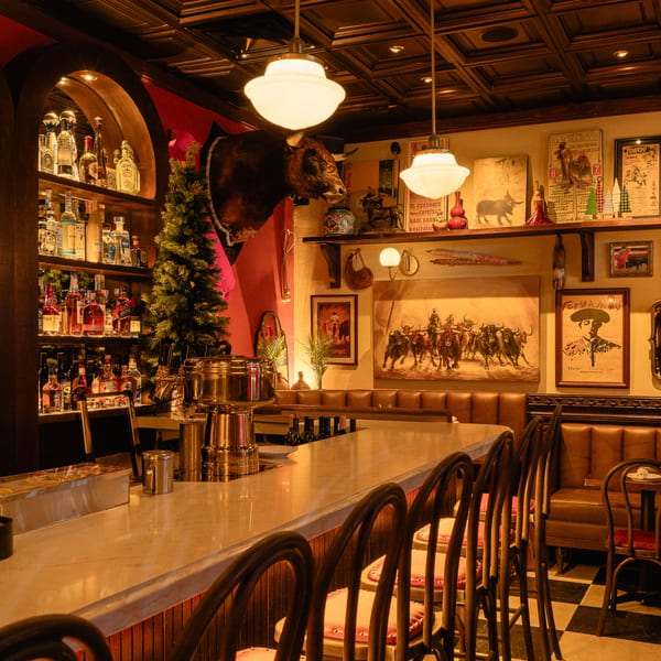 Romesco Mexiterranean Bistro's bar with a mounted bull head, liquor bottles, and bullfighting art.