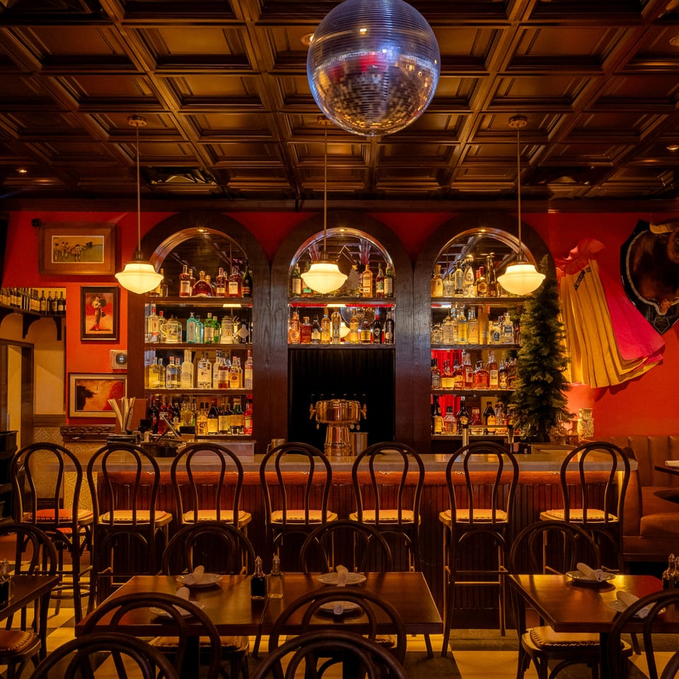 Romesco Mexiterranean Bistro's bar area with a disco ball, liquor shelves, and dining tables.