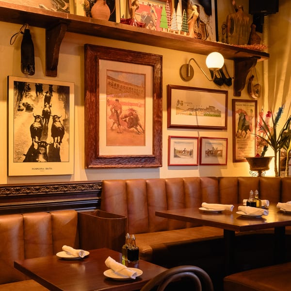 Cozy Romesco Mexiterranean Bistro interior with leather booths, dark wood tables, and bullfighting art.