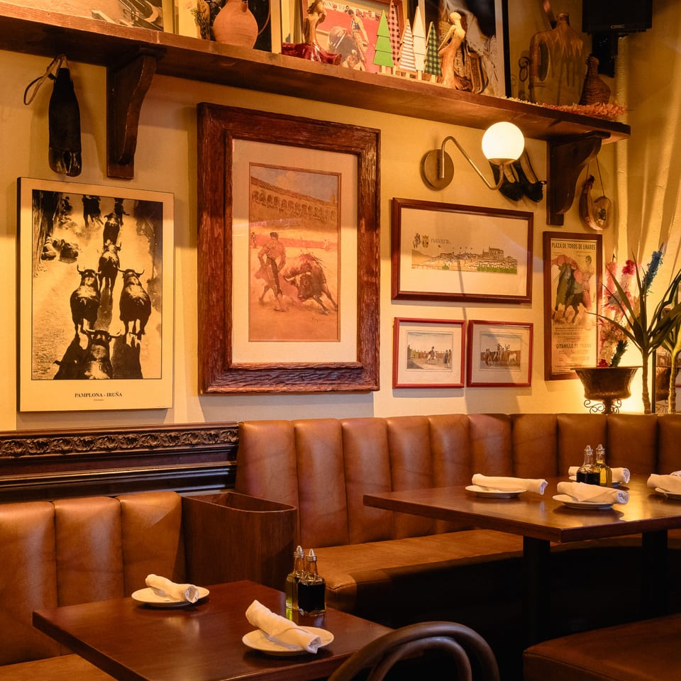 Cozy Romesco Mexiterranean Bistro interior with leather booths, dark wood tables, and bullfighting art.