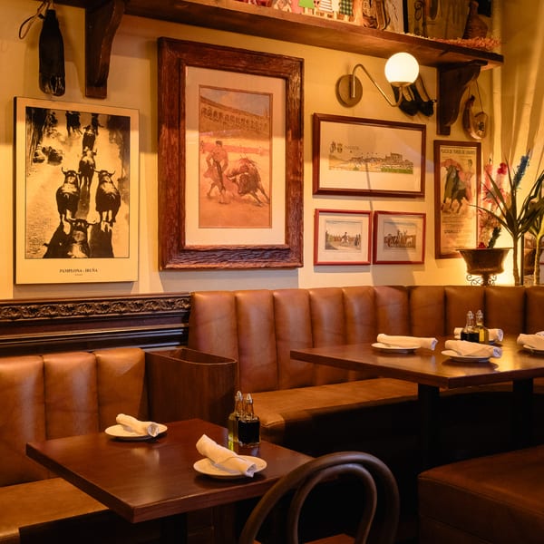Cozy Romesco Mexiterranean Bistro interior with leather booths, dark wood tables, and bullfighting art on the walls.