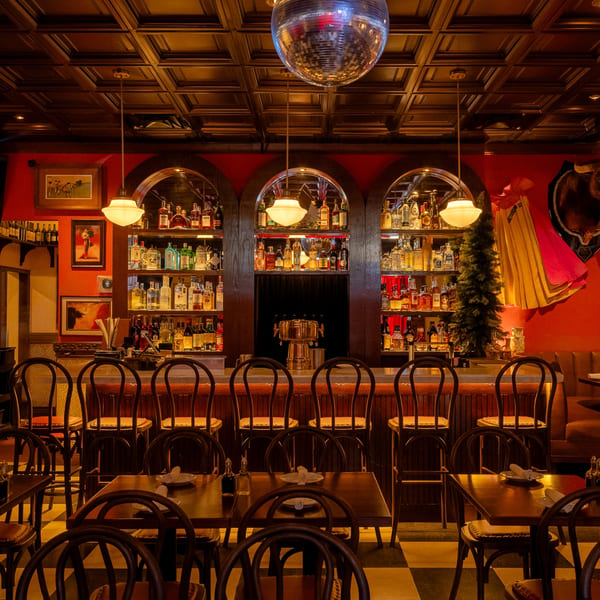 Romesco Mexiterranean Bistro's bar area with a disco ball, liquor bottles, and dining tables.