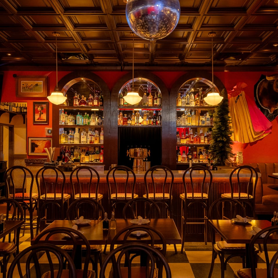 Romesco Mexiterranean Bistro's bar area with a disco ball, liquor bottles, and dining tables.